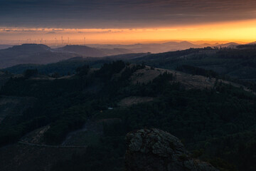 The beautiful landscape of the Sauerland region in Germany, seen from Bruchhausen Steine. Hills dotted with wind turbines, illuminated by the rising sun.
