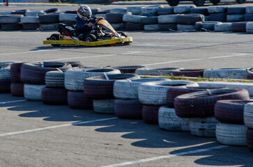 Dynamic Action Shot of Kid Driving Yellow Kart.Child Kart Racer Surrounded by Tire Barriers
