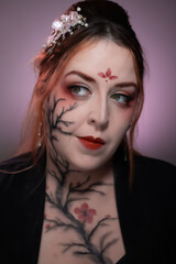 Artistic makeup inspired by sumi-e technique, featuring cherry blossom branches painted across face and neck with elegant red accents