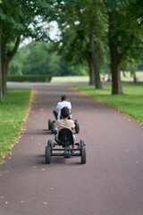 Kinder mit einem Tretauto, Kettcar unterwegs im Stadtpark Rotehorn in Magdeburg