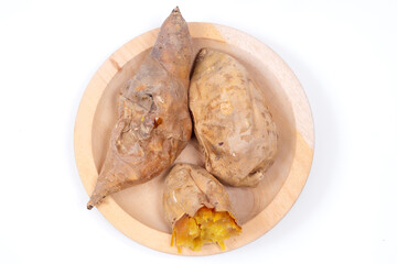 Roasted Cilembu sweet potatoes on wooden plate, with one cut open showing golden caramelized flesh, tasty organic root vegetable from Indonesia.