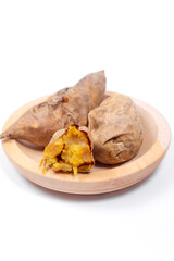 Delicious roasted Cilembu sweet potatoes served on wooden plate, one cut open showing golden caramelized flesh, nutritious organic root vegetable popular in Indonesia and Asia.