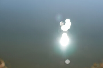 Abstract blurred sunlight reflections on water surface creating soft focus bokeh effect.