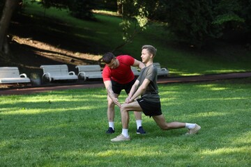 Obraz premium Young man exercising with professional personal trainer outdoors