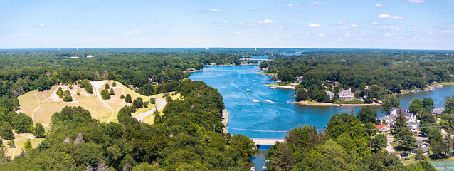 Aerial View of Norton Shores Michigan with Scenic Lake and Forest Landscape” Stunning aerial drone view of Norton Shores, Michigan, featuring a vibrant blue lake surrounded by lush green forest, 