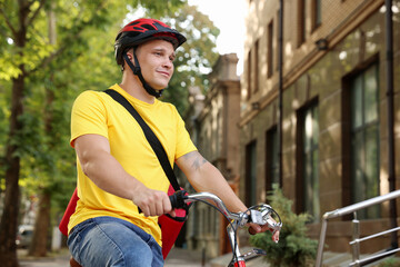 Naklejka premium Courier with thermo bag riding bicycle outdoors, low angle view. Food delivery service