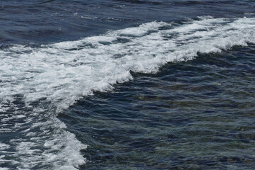 Pacific shore with white wave and blue ocean