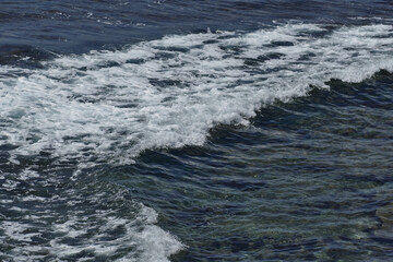 Pacific shore with white wave and blue ocean