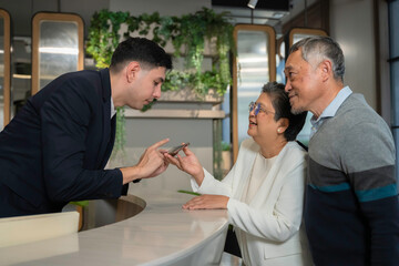 Fototapeta premium Friendly concierge assisting senior couple at modern hotel reception desk, providing direction with warm service and welcoming hospitality in a stylish urban environment.