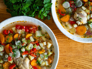 Vegetable soup with broad bean and chicken meat on wooden table