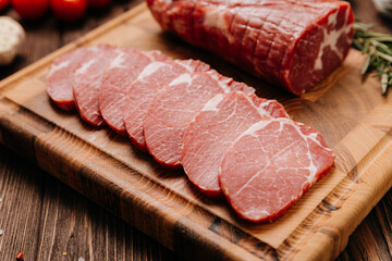 Fresh raw pork loin with rosemary on a wooden cutting board, perfect for cooking or grilling recipes