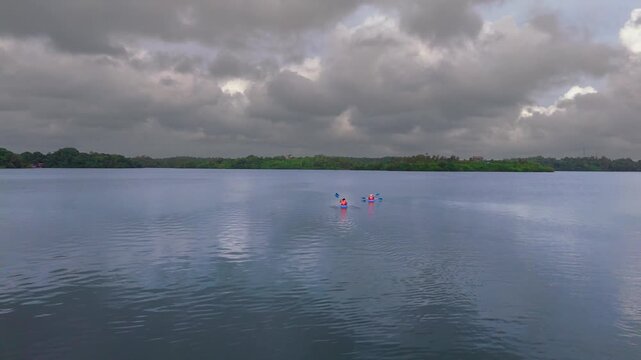 Evening Drone Shot of 4 Kayakers Gliding Across a Calm Lagoon in Moody Light
