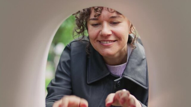 Woman smiling when receiving delivered package and letters from outdoor mailbox on street
