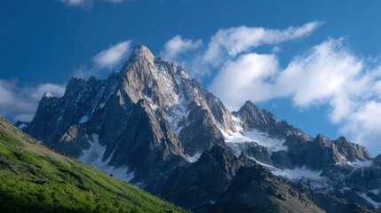 Fototapeta premium Jagged mountain peaks reaching into a clear vibrant blue sky with scattered clouds