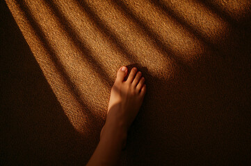 Close-up high angle shot of a bare foot resting on a textured surface with dramatic light and shadow