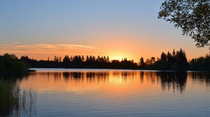 Obraz premium Serene lakeside sunset with silhouetted trees and reflective water