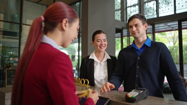 Customer making payment at hotel reception using credit card terminal, close-up of transaction process