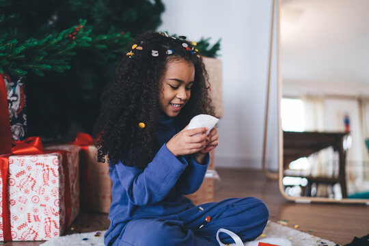Happy little looking at gift box in hands while sitting on floor