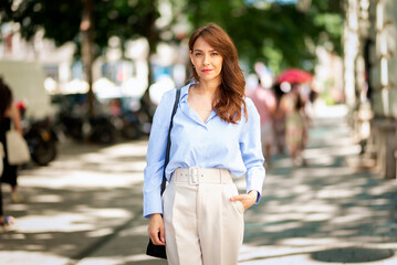 Fototapeta premium Cheerful msiling brunette haired woman walking on the city street