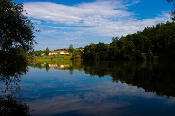 Fototapeta premium Tranquil Boskovštejn pond in South Moravia, Czech Republic, surrounded by greenery and rural landscape.