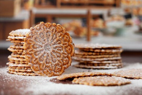 Stacks of Pizzelles on a Bakery Counter Covered in Powdered Sugar