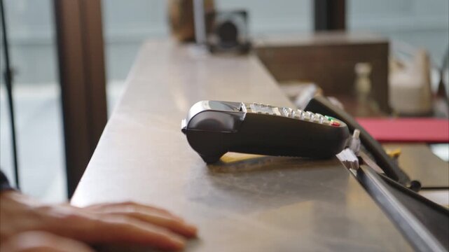 Customer making payment at hotel reception using credit card terminal, close-up of transaction process