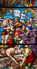 Fototapeta premium Stained glass (1914) of The Way of the Cross. Eleventh station: Jesus is nailed to the cross.