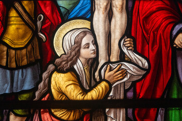Stained glass (1914) of Saint Mary Magdalene at the feet of Christ on the cross. © Joan