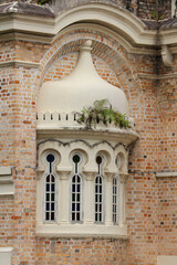 Bay window (oriel) is a protruding decorative window/niche in a facade with a dome and arched windows on a brick facade in Kuala Lumpur, Malaysia.