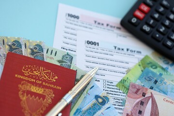 Bahraini dinar money bills and calculator with tax form on blue. Taxation and accounting concept