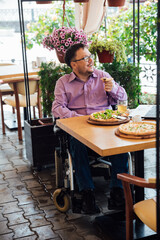 Man in wheelchair dining in street restaurant