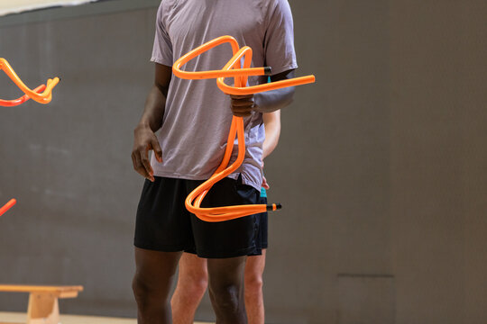 Diverse male training partners gripping bright agility poles standing in gymnasium