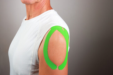 Senior Man with Kinesio tape on his shoulder for chronic pain relief 