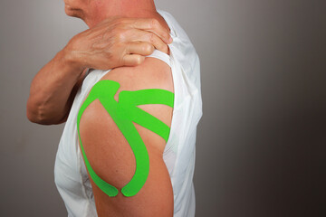 Senior Man with Kinesio tape on his shoulder for chronic pain relief 