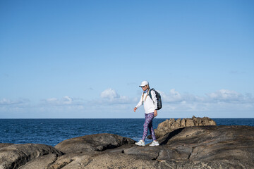 a woman hiking by the ocean on rocky terrain