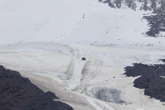 A chain of climbers and a snowcat climbs Mount Elbrus from a height of 4,000 m. - Powered by Adobe