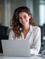 Naklejka premium young businesswoman smiling and working on a laptop while sitting at her desk in an office no logos no brands