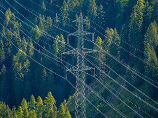 Aerial view of power line pylon in mountaineous area in Switzerland through valley in Canton of Valais.
