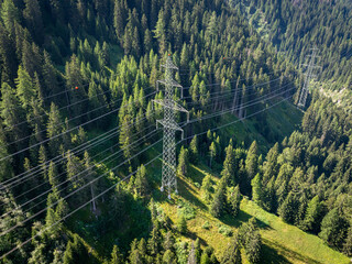 Aerial view of power line pylon in mountaineous area in Switzerland through valley in Canton of Valais. Electricity grid in Homs, Switzerland.