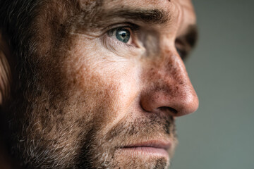 Fototapeta premium Close-up of a contemplative man's face highlighting detailed facial features and blue eye
