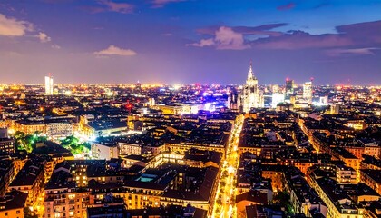 Naklejka premium A high-angle view of illuminated city streets and buildings at night, showcasing a vibrant cityscape with glowing lights.