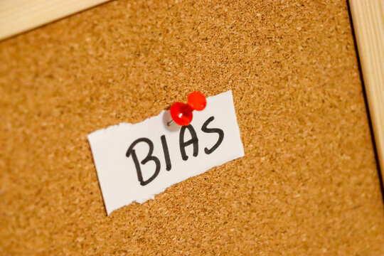 A handwritten note displaying the word BIAS pinned to a corkboard. This image conveys concepts related to perception, judgment, and personal perspectives, suitable for editorial use.