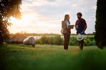 Happy farm owner and financial advisor going through paperwork at sunset. © Drazen