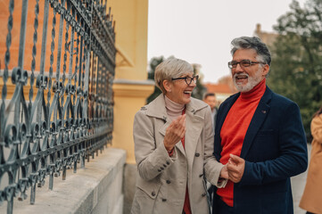 Happy senior couple walking and talking by wrought iron fence
