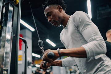 Determined athlete performing triceps pushdown exercise in gym