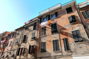 Fototapeta premium Line of facades of chipped, paint-faded houses (some renewed) on Via Roma Street under the warm light of early sunset. Vernazza-Cinque Terre-Italy-267
