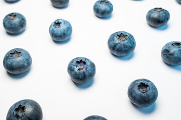Arrangement of scattered blueberries on a white background, highlighting their circular shapes and subtle blue patina. Great for a simple product shot or a minimalist food design element.