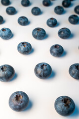Arrangement of scattered blueberries on a white background, highlighting their circular shapes and subtle blue patina. Great for a simple product shot or a minimalist food design element.