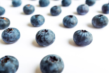 Arrangement of scattered blueberries on a white background, highlighting their circular shapes and subtle blue patina. Great for a simple product shot or a minimalist food design element.