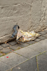Vertical composition of crumpled umbrella with torn strap on cobbles beside a plastered wall, captured as a documentary image about littering.